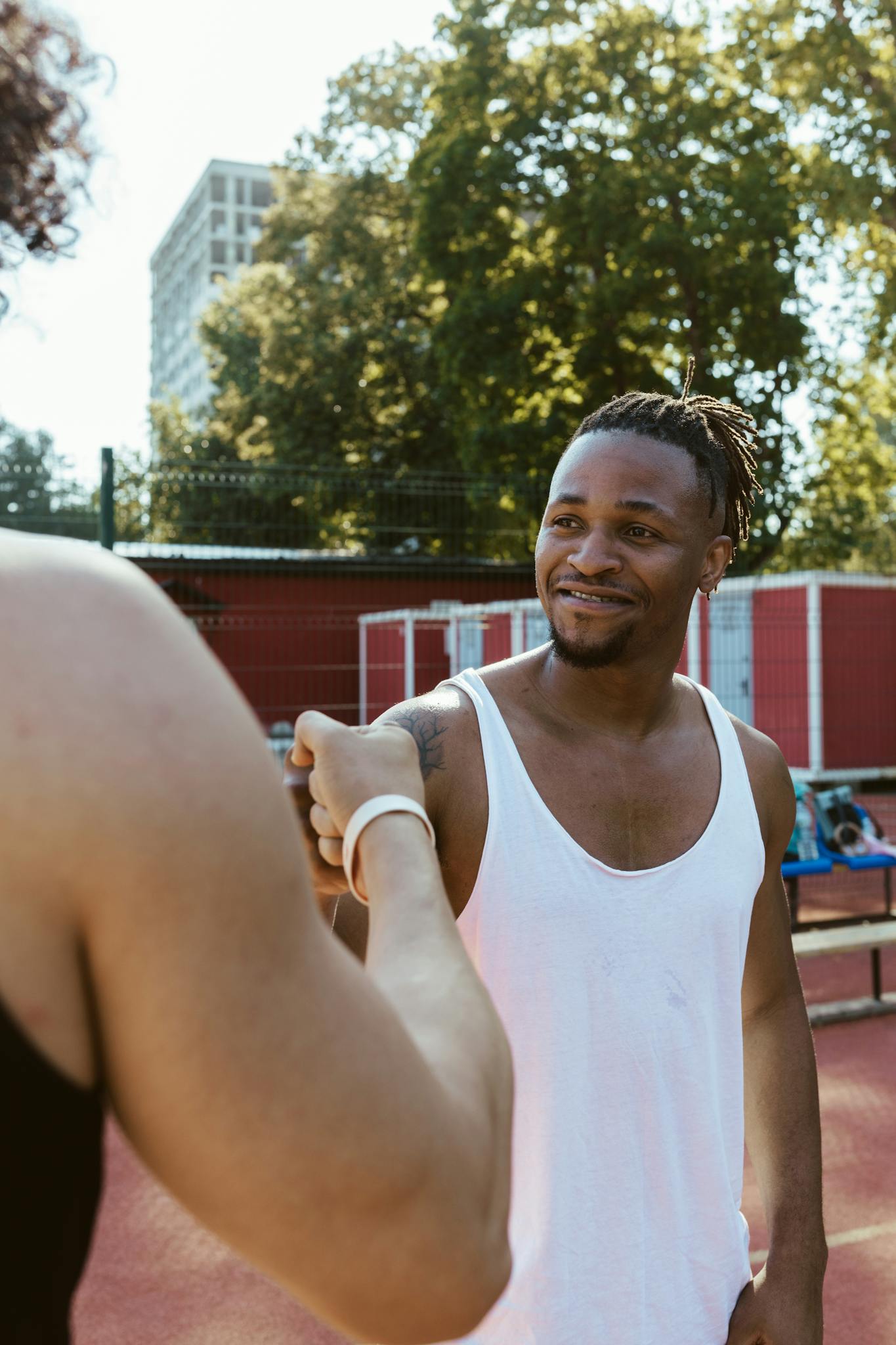 Friendly encounter between two basketball players outdoors on a sunny day.